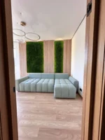 Paneele aus Flachmoos mit Beleuchtung und Leisten an den Wänden im Innenraum des Wohnzimmers mit hellem Sofa und Leisten