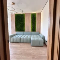 Paneele aus Flachmoos mit Beleuchtung und Leisten an den Wänden im Innenraum des Wohnzimmers mit hellem Sofa und Leisten