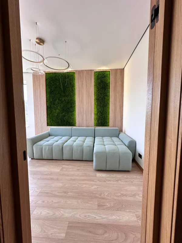 Paneele aus Flachmoos mit Beleuchtung und Leisten an den Wänden im Innenraum des Wohnzimmers mit hellem Sofa und Leisten