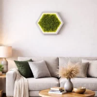 Beleuchtetes Hexagon-Wandbild aus grünem Islandmoos in einem weißen Rahmen mit LED-Konturbeleuchtung, aufgehängt an einer grauen Wand in einem modern eingerichteten Wohnzimmer