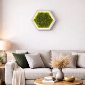 Beleuchtetes Hexagon-Wandbild aus grünem Islandmoos in einem weißen Rahmen mit LED-Konturbeleuchtung, aufgehängt an einer grauen Wand in einem modern eingerichteten Wohnzimmer